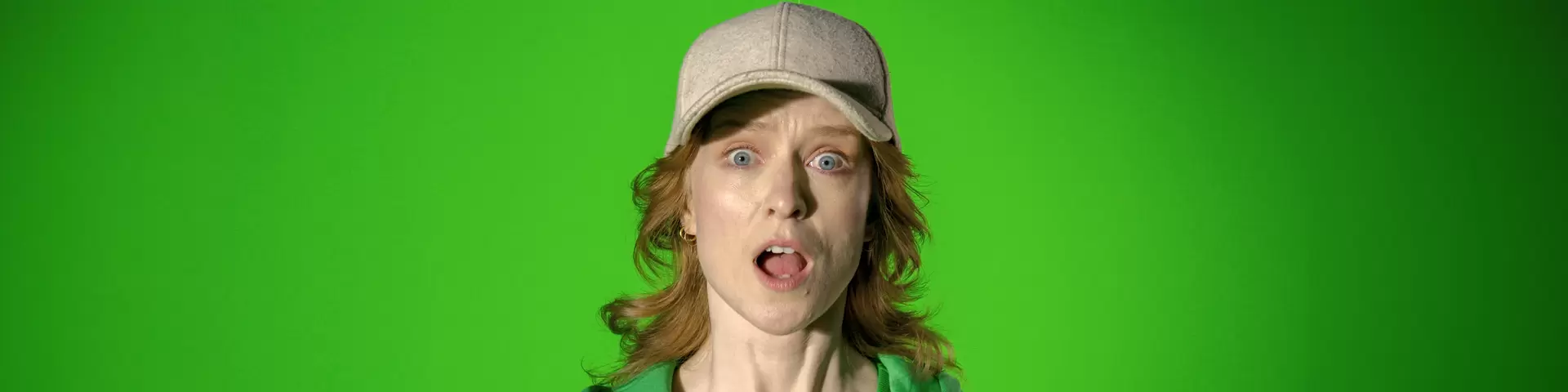 Kvinna mot grön bakgrund som ser chockad ut.