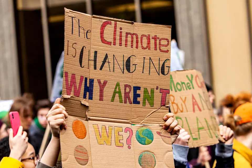 Foto på demonstration med ett plakat med texten The climate is changing, why aren't we?