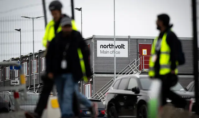 Anställda från Northvolt lämnar anläggningen, med Northvolt skylt i bakgrunden